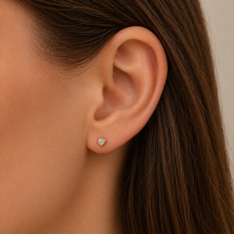 14k yellow gold diamond heart stud earring worn in lobe piercing, showing fit and size on model