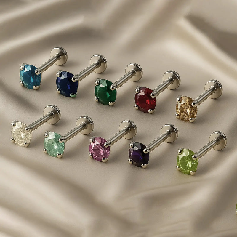 Prong-set gemstone flat back labrets in multiple birthstone colors on silver posts arranged on satin