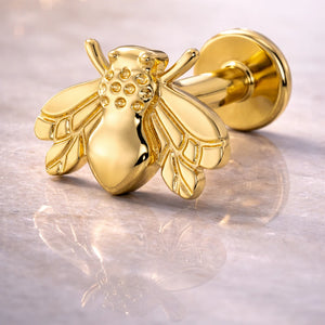 14K yellow gold bee flat back labret close-up on marble, showing engraved wing and thorax detail