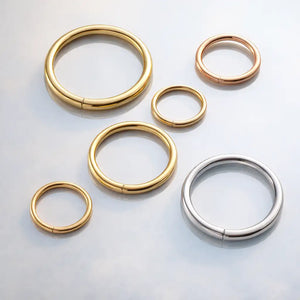 18K gold seam ring hoops in yellow, rose, and white gold shown in multiple sizes on gray surface