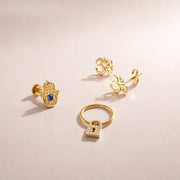 14k yellow gold diamond lock seam ring styled with hamsa and Om studs in a jewelry flat lay