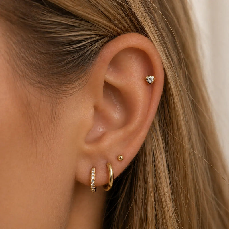 14k gold diamond heart flat back stud shown in helix piercing as part of an ear stack