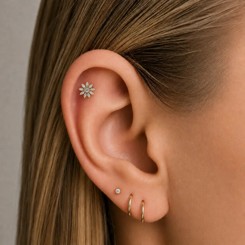 Close-up of an ear wearing multiple earrings and a diamond flower helix earring.