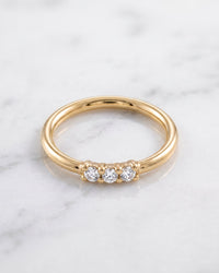 Seam rings - 14k yellow gold seamless hoop with three front-facing diamonds on white marble