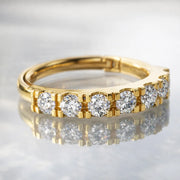 14k yellow gold CZ clicker ring resting flat on reflective marble surface, stones facing forward