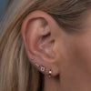 Gold flatback labret stud and CZ earrings styled on model's ear showing lobe and cartilage placement