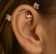 14k gold lotus industrial barbell shown in model's cartilage piercing for fit and scale