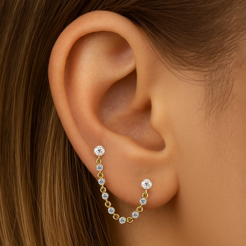 14K yellow gold Lyra CZ connector studs linking two ear piercings with draped gem chain on model