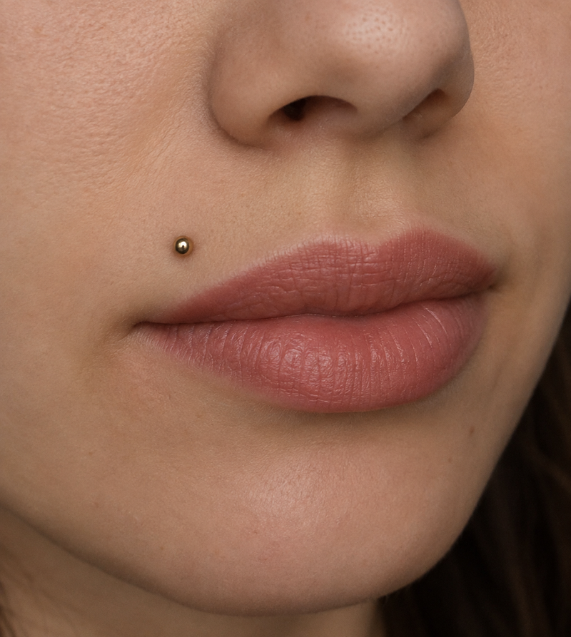 Madonna piercing with a gold ball flat back stud on the upper lip