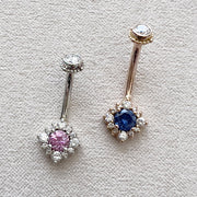 Two 14k gold halo navel rings side by side: white gold with pink sapphire and yellow gold with blue sapphire