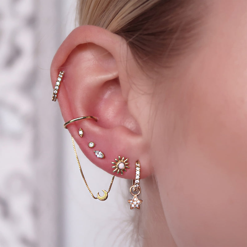 Gold opal sun stud end worn in earlobe piercing, styled with curated ear stack