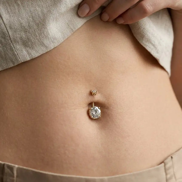 Close-up of a belly button ring on a person wearing beige pants.