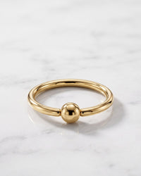 Nipple rings and hoops - 14k yellow gold fixed bead ring on white marble