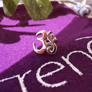 14k rose gold Om ohm stud earring resting on purple velvet surface, lifestyle close-up