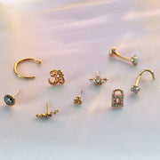 Marquise lotus pushpin end styled among assorted gold piercing jewelry flatlay