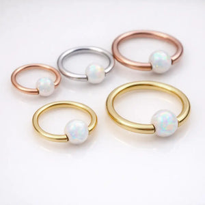 White opal captive bead rings in 14K yellow gold, rose gold, and white gold shown in multiple sizes