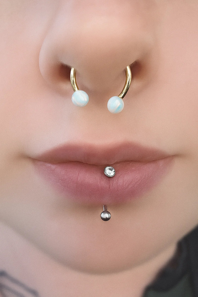 Teal opal 14k gold circular barbell worn in a septum piercing, showing fit and placement on model