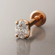 14k rose gold 3mm oval-cut diamond flat back labret, angled studio shot showing 4-prong setting and disc back