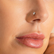Oval diamond nose ring in white gold worn in nostril piercing, closer angled view on model