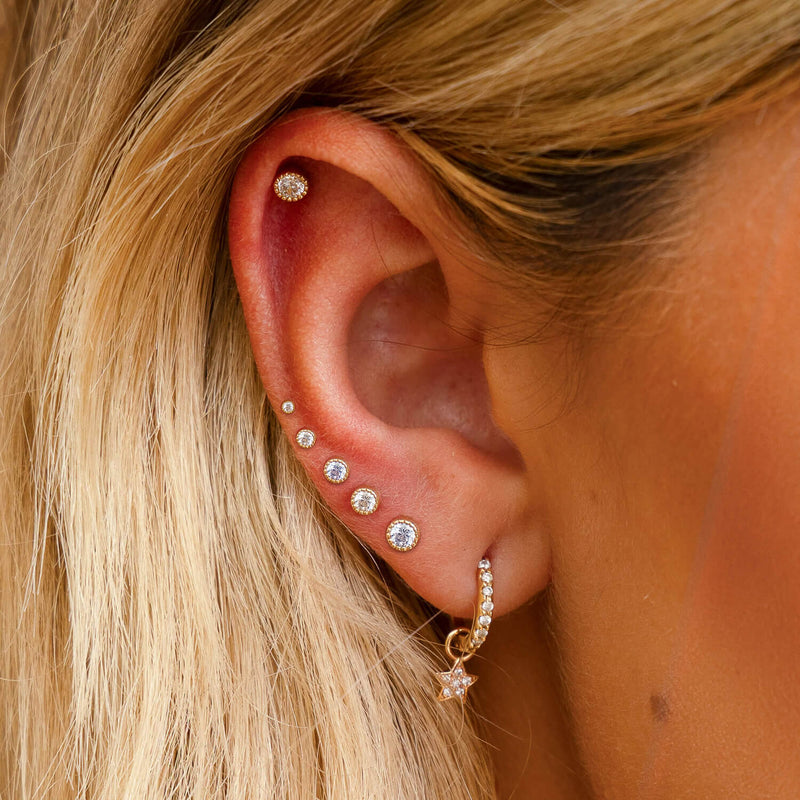 Diamond perlage flat back studs worn across helix and cartilage piercings on model's ear
