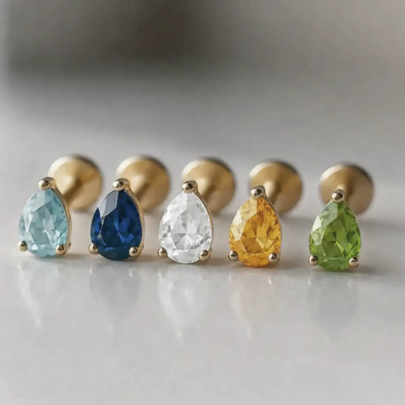 Five 14k gold pear-cut gemstone flat back studs in a row showing aqua, blue, white, citrine, and peridot