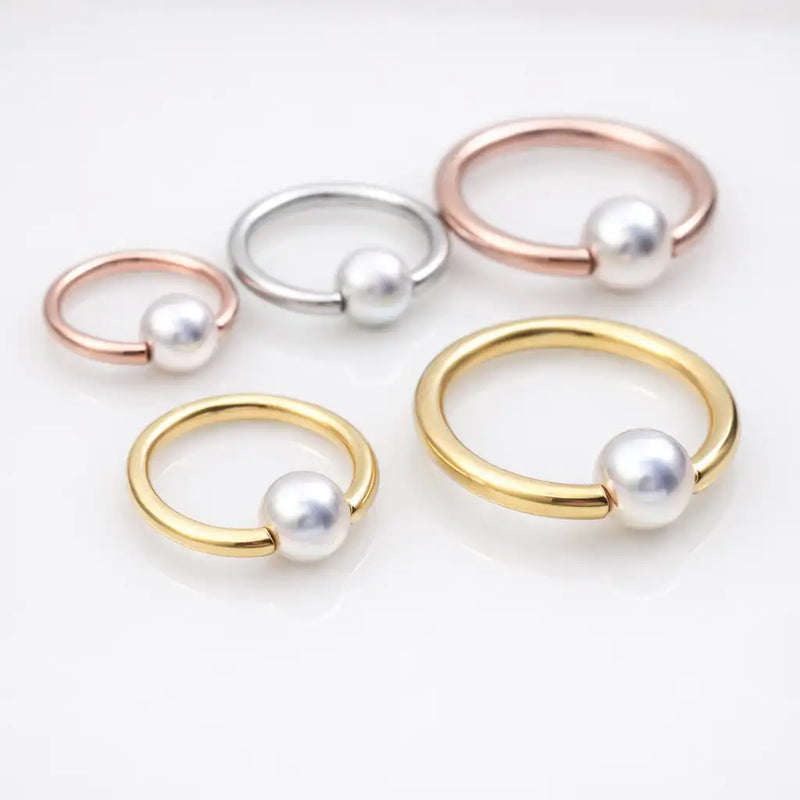 Pearl captive bead rings styled in yellow gold, rose gold, and silver tones showing various ring and pearl sizes
