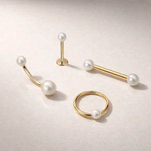 14K yellow gold pearl body jewelry collection showing straight barbell alongside labret, curved barbell, and hoop