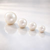Genuine cultured pearl captive bead replacements shown in four sizes from 3mm to 6mm on reflective surface