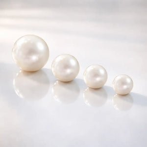 Genuine cultured pearl captive bead replacements shown in four sizes from 3mm to 6mm on reflective surface