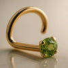 14K yellow gold peridot nose ring twist style with prong-set green stone, angled studio view