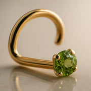 14K yellow gold peridot nose ring twist style with prong-set green stone, angled studio view