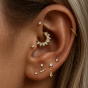 14K yellow gold dew drop labret stud worn in lobe piercing, styled with curated gold ear stack