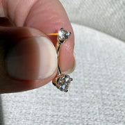 14k yellow gold diamond belly ring held between fingers to show petite curved barbell size