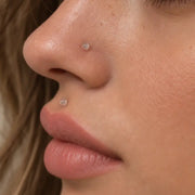 Clear glass nostril retainer and labret retainer worn on a model, close-up of the nose and lower lip piercings