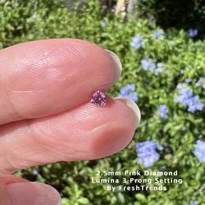 2.5mm genuine pink diamond piercing end pinched between fingers outdoors for size reference