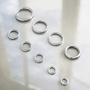 18K white gold plain clicker hoops in multiple sizes and gauges scattered on frosted glass surface