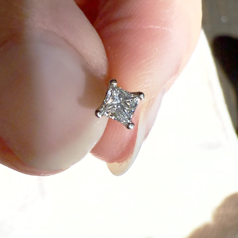 3mm princess-cut diamond flat back stud end pinched between fingertips for size reference