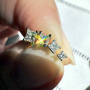 Three graduating princess-cut diamond ends balanced on fingernail showing rainbow light dispersion