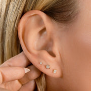 Princess-cut diamond flat back studs worn in triple lobe piercing stack on model's ear