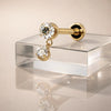 14k yellow gold dual diamond dangle flat back labret resting on glass, showing post and flat back
