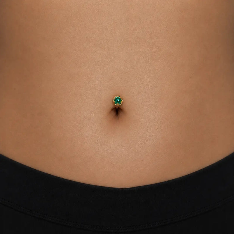 Model wearing the Reina Zambian Emerald Crown Floating Navel Ring in 14k gold
