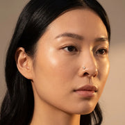 4mm Reina rose cut diamond nose ring in 14k yellow gold worn in a nostril piercing, close-up on a model
