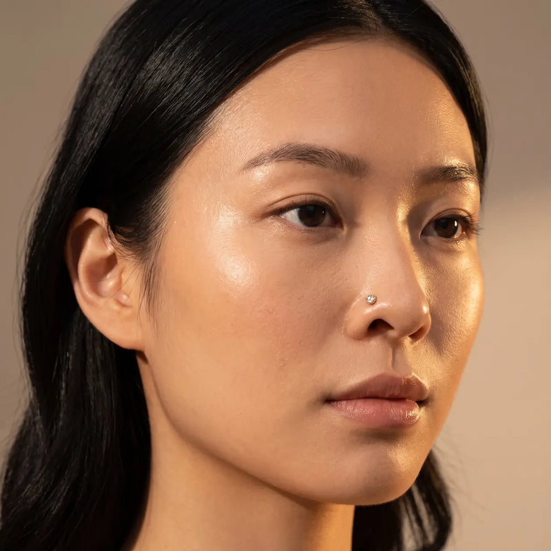 4mm Reina rose cut diamond nose ring in 14k yellow gold worn in a nostril piercing, close-up on a model