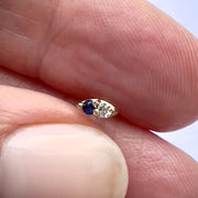 14K yellow gold sapphire and diamond nose ring held between fingers to show tiny actual size