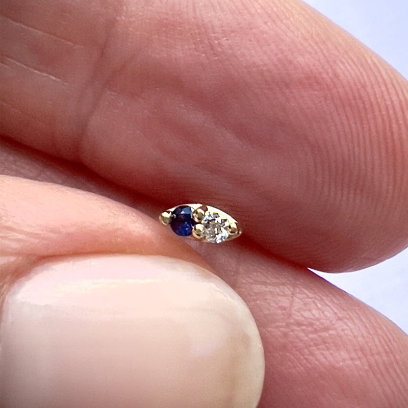 14K yellow gold sapphire and diamond nose ring held between fingers to show tiny actual size