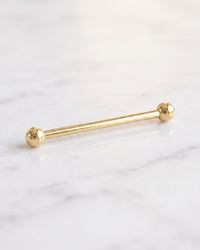 Industrial barbells - long plain 14k yellow gold Classic Industrial barbell with ball ends on white marble