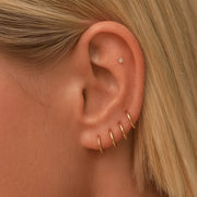 14k yellow gold clicker hoops styled in stacked lobe and cartilage ear piercings on model