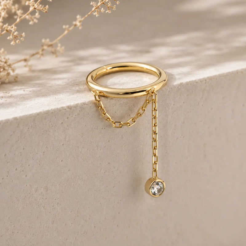 Diamond and yellow gold, a shanty seam ring lifestyle image dangling on a stone surface.