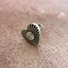 Close-up of 14k white gold diamond sunburst heart flat back stud resting on pink textured surface