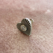 Close-up of 14k white gold diamond sunburst heart flat back stud resting on pink textured surface
